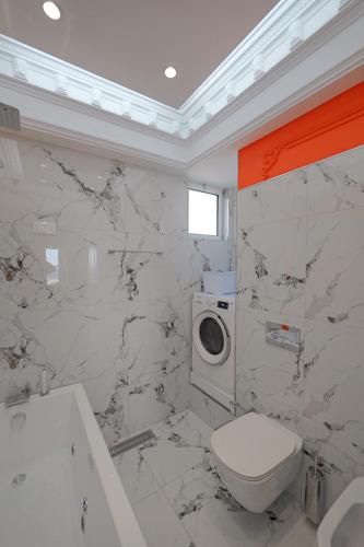a white bathroom with a toilet and a washing machine at New Beach Suite in Sarandë