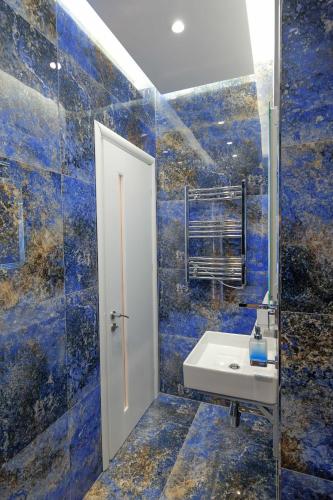 a bathroom with a sink and blue tiled walls at New Beach Suite in Sarandë
