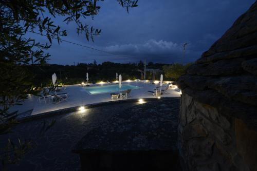 einen Pool mit Stühlen und nachts Licht in der Unterkunft I trulli di Eva in Noci