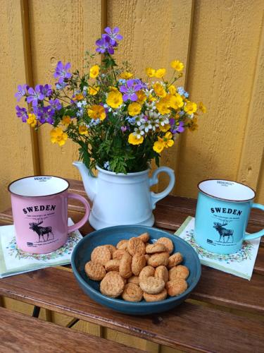 a table with two cups and a plate of cookies and flowers at Ferienhaus Schweden - Hus Else in Gällstad