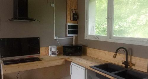 a kitchen with a counter with a television and a sink at Lumineux et proche de tout avec balcon et à côté du bois in Boulogne-sur-Mer