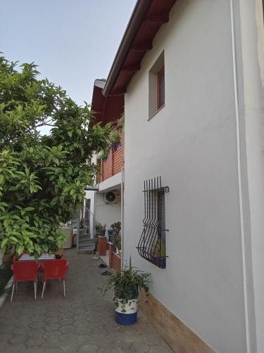 a white building with red chairs and a window at Eni's Villa in Lezhë