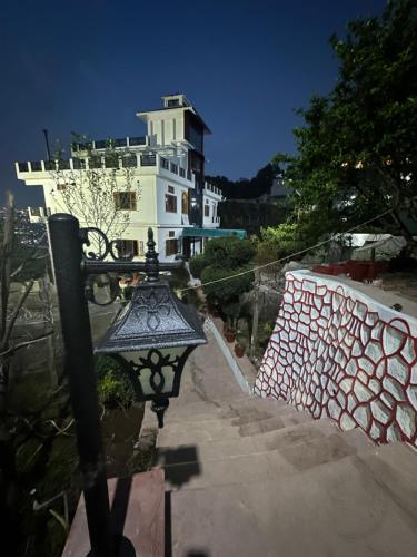 a white house with a fence and a street light at Uttaranchal Homestay in Pithorāgarh