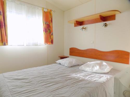 een slaapkamer met een wit bed met 2 kussens bij locationestivale40 Bungalow petit budget océan forêt in Bias