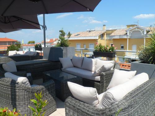 a patio with wicker chairs and tables and an umbrella at Residhome Arcachon Plazza in Arcachon