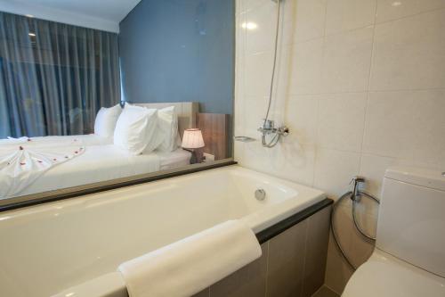 a bathroom with a bath tub and a bed in a mirror at Libra Hotel Nha Trang in Nha Trang
