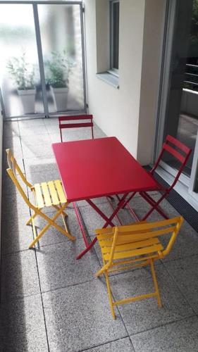 a red table and two chairs next to a table at Appartement Tout Relooké à 10mn des plages ! in Larmor-Plage