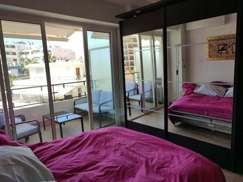 - une chambre avec un lit violet et un balcon dans l'établissement Studio neuf climatisé au cœur de Juan-les-Pins, à Antibes