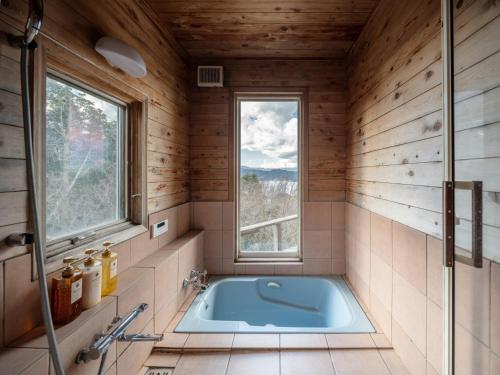 a bathroom with a tub in a room with a window at Oceanic House TAMATEBAKO in Ito