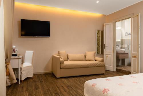 a room with a couch and a television on the wall at Onda Marina Suites in Cagliari