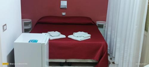 a red room with a bed with towels on it at Almaran B&B Trapani port & city in Trapani