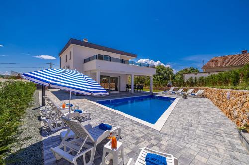 a house with a swimming pool with chairs and an umbrella at Vila KATHARINA s privatnim bazenom in Žgaljić