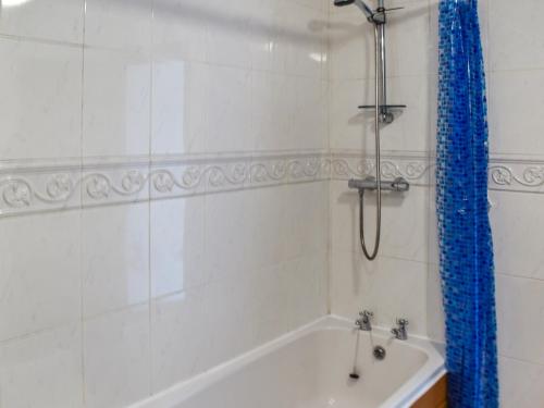 Hay Barn - Uk46197 في Budock Water: حمام مع حوض استحمام ودش مع ستارة دش زرقاء