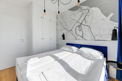 a bedroom with a white bed with a blue headboard at GRANO FLATS - Sobieszewo - Baltic Porto in Gdańsk