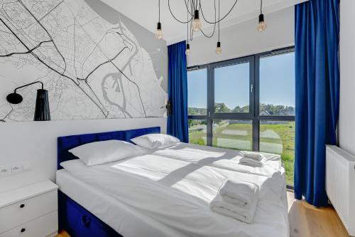 a bedroom with a large bed with blue curtains at GRANO FLATS - Sobieszewo - Baltic Porto in Gdańsk