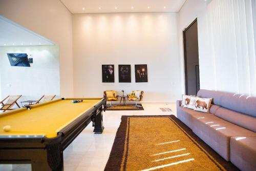 a living room with a pool table and a couch at Casa c/ Piscina de borda infinita e vista p/ Lago in Caldas Novas