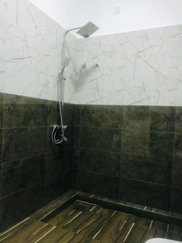 a shower in a bathroom with black and white tiles at Ananyah Villa in Trincomalee