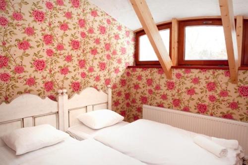 2 Betten in einem Schlafzimmer mit Blumen an der Wand in der Unterkunft Piena muiža - Berghof Hotel & SPA in Sieksāte