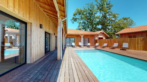 une piscine avec une terrasse en bois à côté d'une maison dans l'établissement Villa avec clim et piscine chauffée Arès Cap Ferret, à Arès
