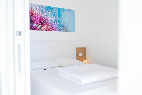 una camera bianca con un letto e un dipinto sul muro di I Bordin Home a Nettuno