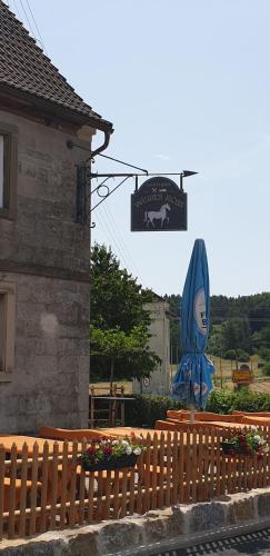 a wooden fence with a sign next to a building at Gasthaus Weißes Ross in Burghaslach