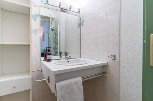 une salle de bain blanche avec un lavabo et un miroir dans l'établissement Le Barclay - Studio proche de la plage, à La Teste-de-Buch