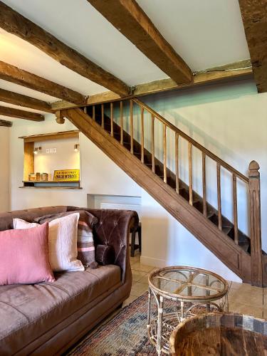 a living room with a couch and a staircase at Gîte Le Four à Pain 6 personnes sur le domaine du Manoir du Rigouneix in Saint-Angel