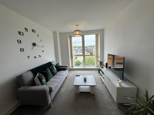 a living room with a couch and a clock on the wall at Luxury 1 Bed Apartment Hemel Hempstead Sleeps 4 Luton Airport Nearby in Hemel Hempstead