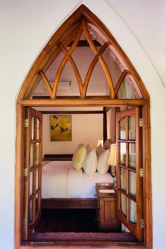 a bedroom with a large arched window with a bed at The Postcard Saligao in Calangute