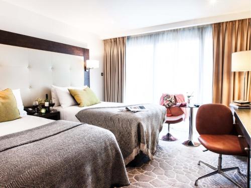 um quarto de hotel com duas camas e uma secretária em The Address Connolly em Dublin