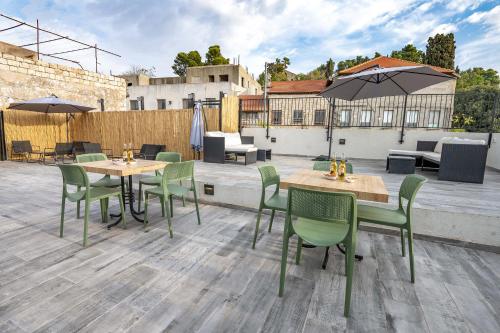 a patio with tables and chairs and an umbrella at ארגמן סוויטות בוטיק in Safed