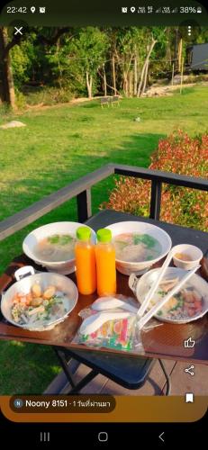 a picnic table with plates of food and orange juice at Riverhill khaoyai บ้านกล่อง in Ban Bung Toei