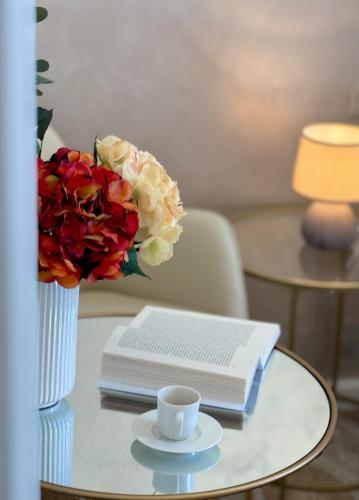 a table with a vase of flowers and a book at Home To Salerno B&B in Salerno