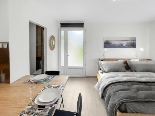 ein Wohnzimmer mit einem Bett, einem Tisch und einem Sofa in der Unterkunft Studio entre Bordeaux et l'Atlantique - Jardin in Saint-Médard-en-Jalles