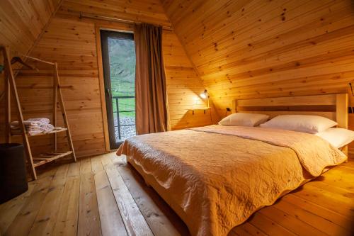 a bedroom with a bed in a wooden cabin at Sunset Cottage Kazbegi in Kazbegi