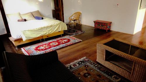 a bedroom with a bed and a living room with wooden floors at Ladakh Eco House in Leh