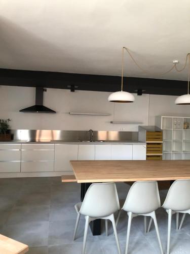 a kitchen with a wooden table and white chairs at savastyana in Riudoms