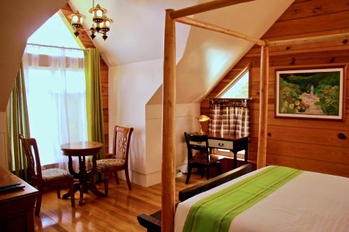 1 dormitorio con cama, escritorio y mesa en Guest Haven Chalet en Baguio