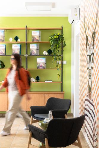 a woman walking through a room with a green wall at Ostello della Gioventù Brindisi in Brindisi