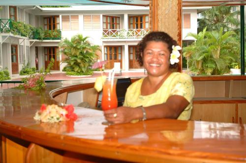 a woman sitting at a table with a drink at Hexagon International Hotel, Villas & Spa in Nadi
