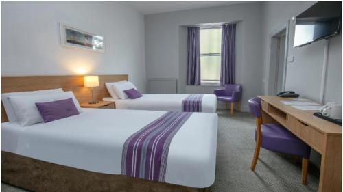 a hotel room with two beds and a desk at Tor Park Hotel, Sure Hotel Collection by Best Western in Torquay