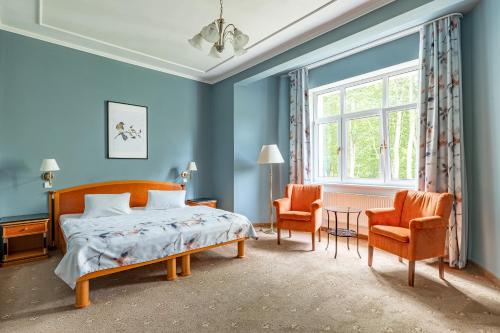 1 dormitorio azul con 1 cama y 2 sillas en Spa & Wellness Hotel Silva en Mariánské Lázně