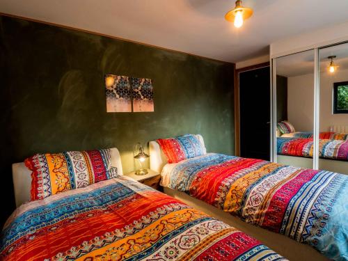 um quarto com 2 camas e cobertores coloridos em Chy Glynn. Luxury lodge with hot tub and views. em St. Agnes