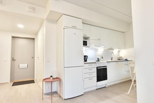 a white kitchen with a refrigerator and a stool at Flamingo Studio, Free Parking, 2 Min to Airport and Spa in Vantaa
