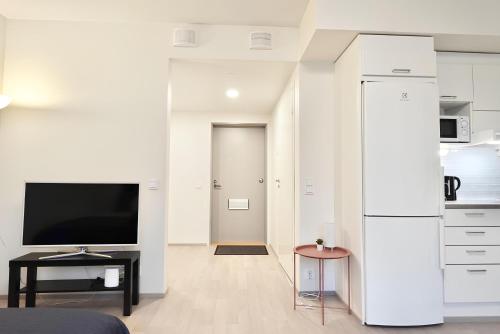 a living room with a tv and a white wall at Flamingo Studio, Free Parking, 2 Min to Airport and Spa in Vantaa