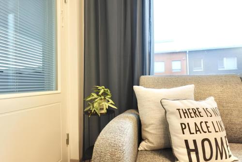 a pillow sitting on a couch next to a window at Flamingo Studio, Free Parking, 2 Min to Airport and Spa in Vantaa