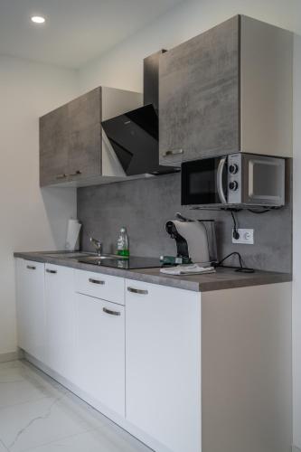 a kitchen with white cabinets and a microwave at Apartmaji Živa in Gornja Radgona