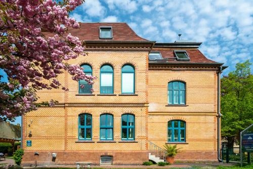 a brick building with blue windows and a tree at Apartments am Schlosspark in Senftenberg