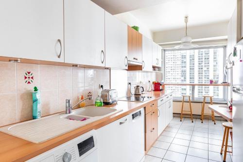 une cuisine avec des placards blancs et une grande fenêtre dans l'établissement GuestReady - Beau Séjour près de la Tour Eiffel, à Paris