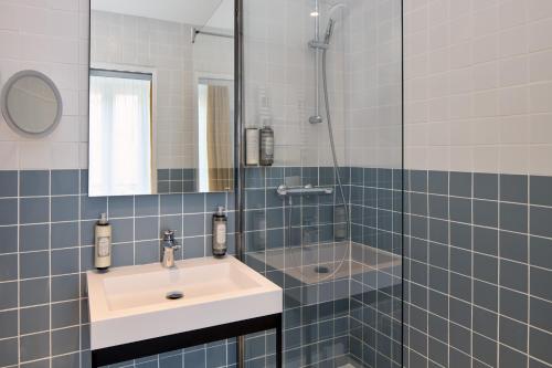 uma casa de banho com um lavatório, um chuveiro e um espelho. em Timhotel Paris du Gare du Nord em Paris